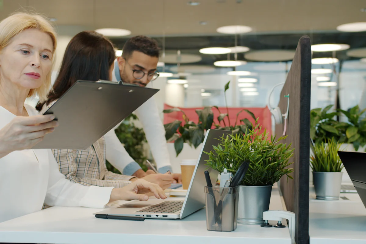 Colleagues discussing a project with laptops and documents in an office.