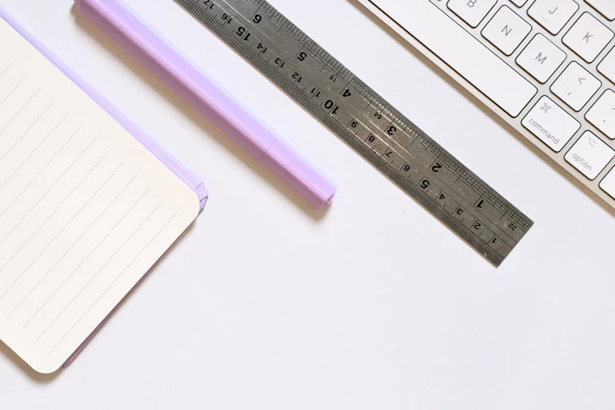 A notebook, ruler, and keyboard arranged on a white surface.
