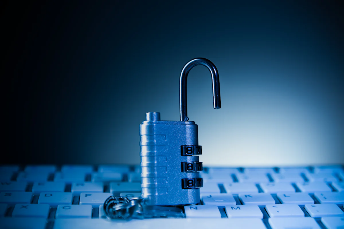 An unlocked padlock resting on a computer keyboard.