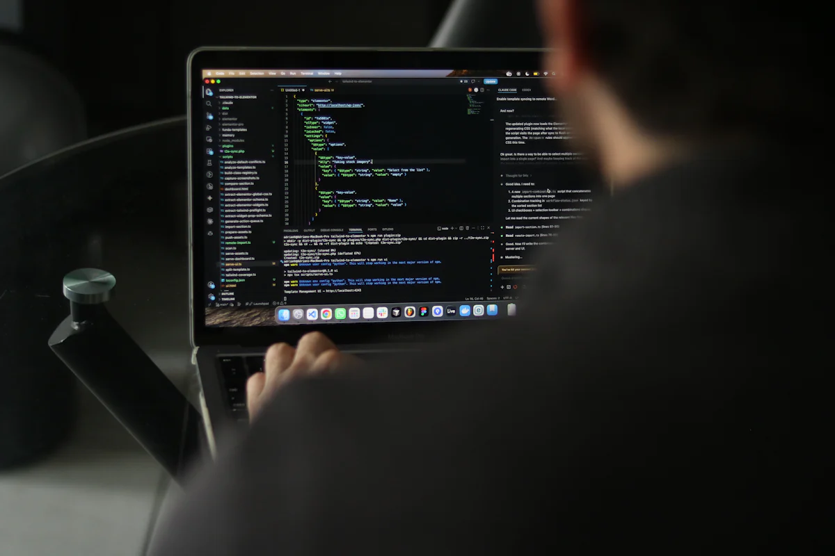 A developer typing on a laptop displaying code.