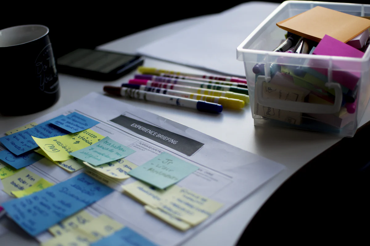 Notes, documents, and highlighters spread across a workshop table.