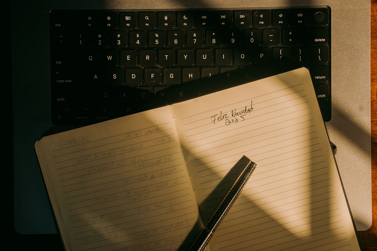 An open notebook with a pen resting on a laptop keyboard.