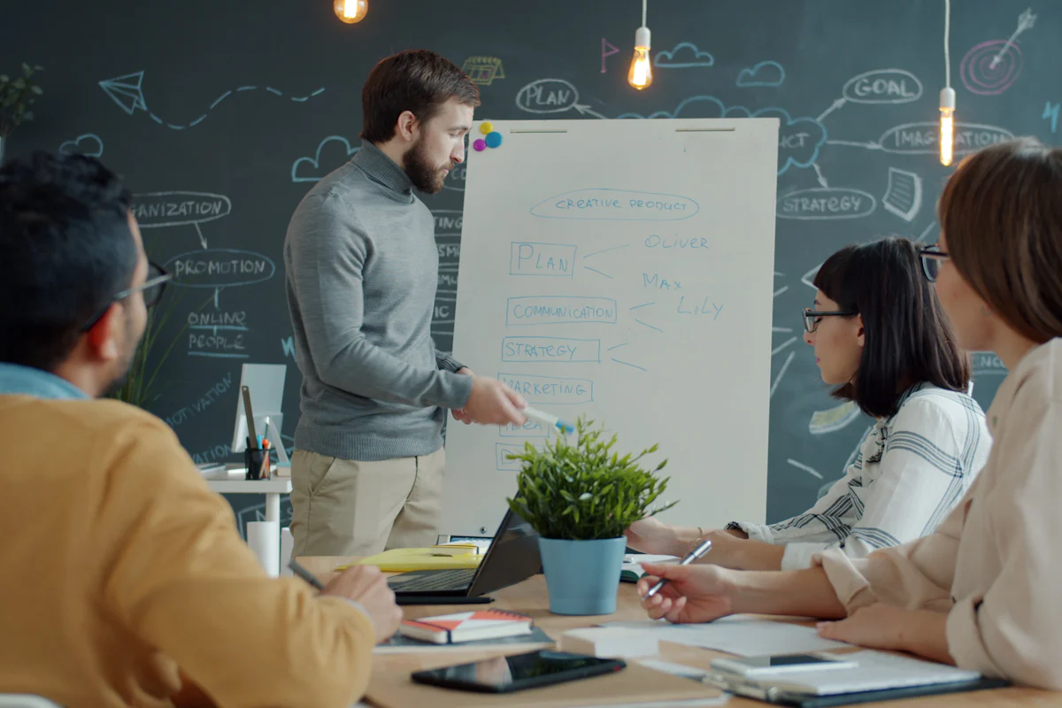 Colleagues discussing a project beside a whiteboard in an office.